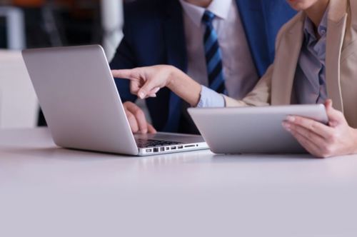 person holdering tablet pointing at laptop