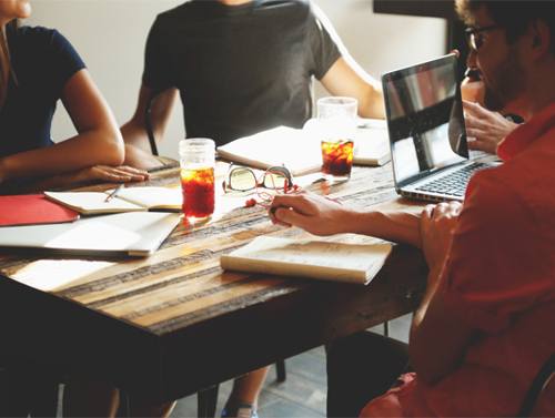 People sat around a table with paperwork and drinks on it