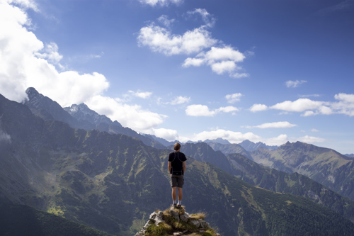 Person on rock looking over valley of mountains