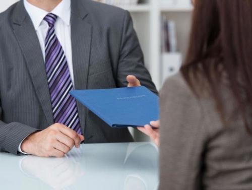 Woman handing folder over to a man News Article